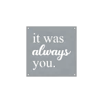 A square steel sign with precision-cut lettering spelling 'it was always you.' The words 'always' are in a cursive script, while the rest are in a simple, sans-serif font. The background is a smooth metallic grey with four small holes at each corner for mounting. The design is minimalist, emphasizing the contrast between the black lettering and the metal background.